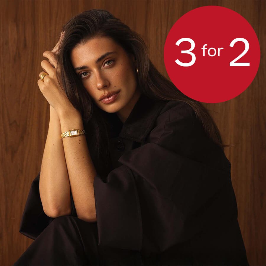 Kvinne sitter mot trevegg og bærer gullklokke og ringer, med en rød sirkel med teksten 3 for 2 øverst til høyre.