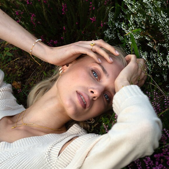 ByBiehl Beautiful World-smykke Halskjede fra byBiehl i gull med byBiehl Beautiful World-anheng som henger ned, med Eiffeltårnet og himmelen i Paris som bakgrunn.