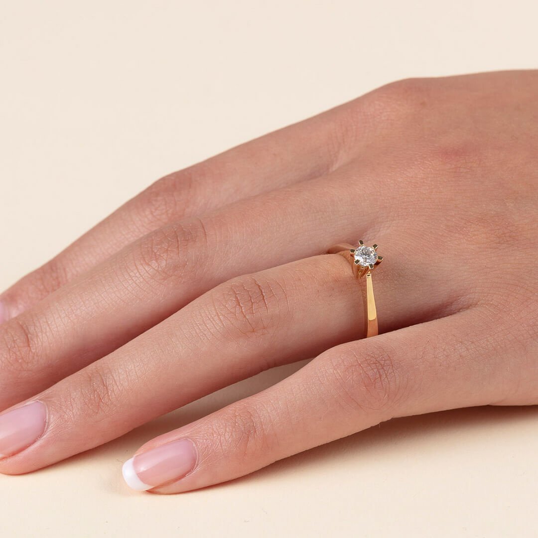 Enstens diamantring Et nærbilde av en godt vedlikehold kvinnehånd med diamantring. Dette er en gullring med seks klør som holder en liten diamant på plass.