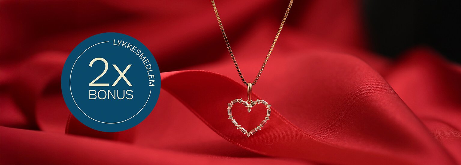 Gullkjede med hjerteanheng ligger på rød satengbakgrunn, med blå sirkeltekst som viser «Lykkesmedlem 2x bonus».