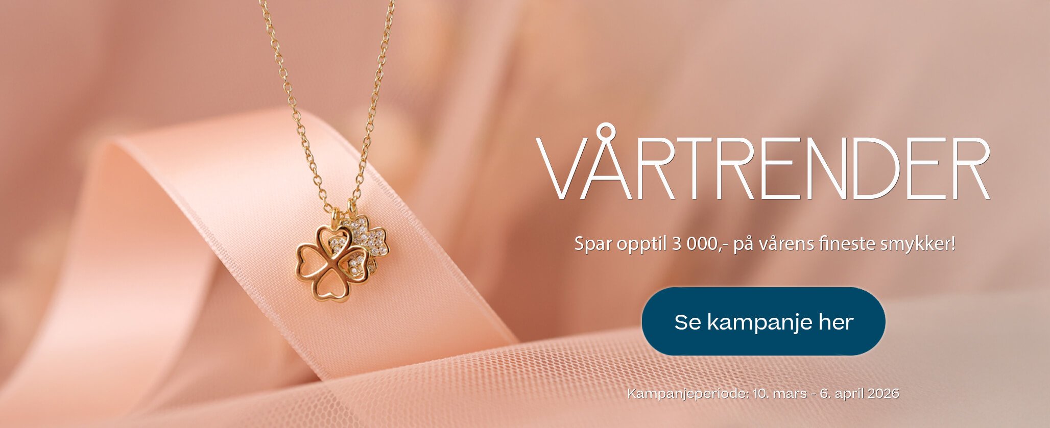 Gullkjede med firkløverformet anheng ligger på lys rosa stoff, med tekst om vårtrender og kampanje på smykker.