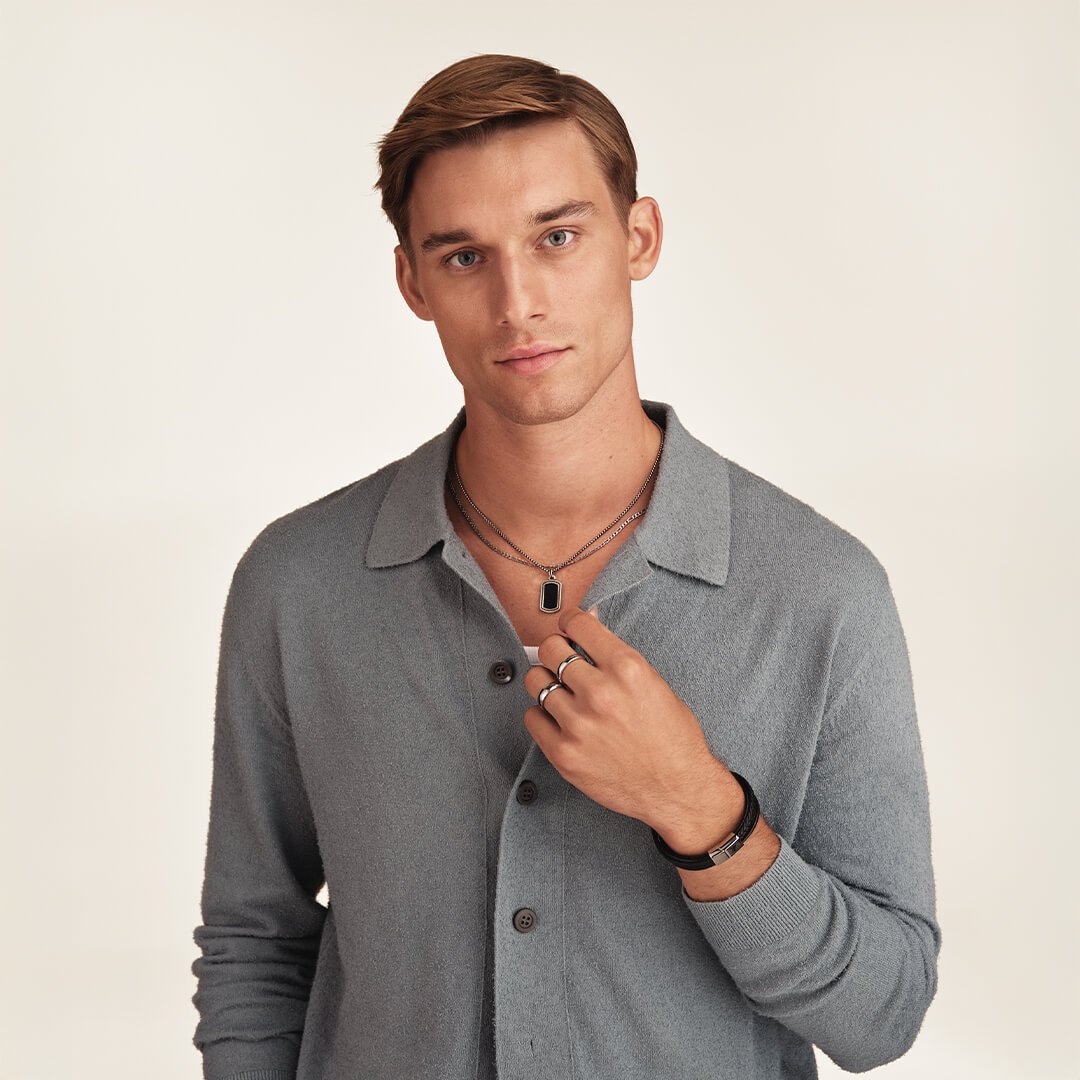 Bjørklund har fine valentinesgaver til han En ung mann med grå cardigan, armbånd i svart skinn og halskjede, som ser rett inn i kamera foran beige bakgrunn