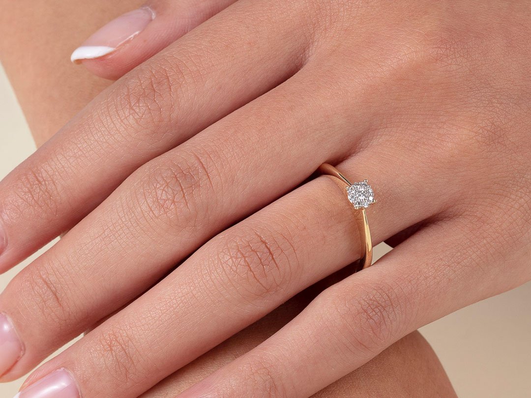 En hånd med en vakker ring med en liten diamant, ligger over en arm som å kunne vise frem ringen bedre i bildet.
